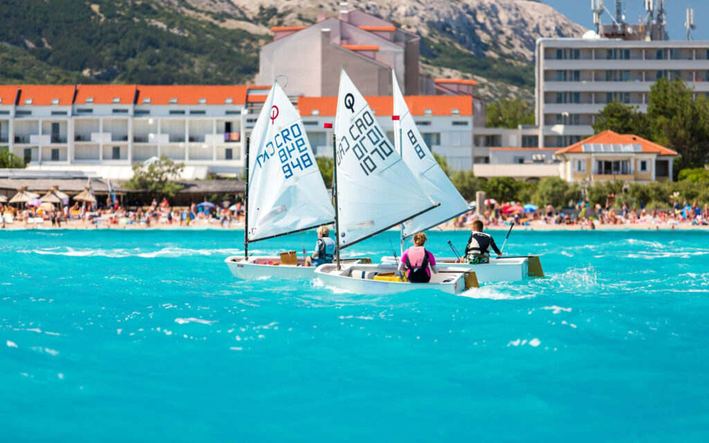 Djeca na jedrilicama Optimist pred Velom plažom u Baški